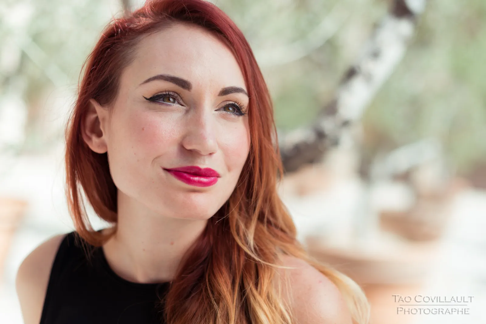 Close-up portrait of a red-haired woman outdoors.
