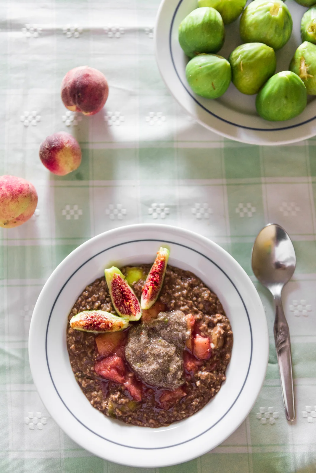 Dessert bowl topped with figs beside green citrus fruit.