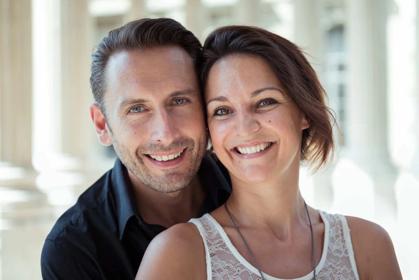 Couple embracing and posing among stone columns.