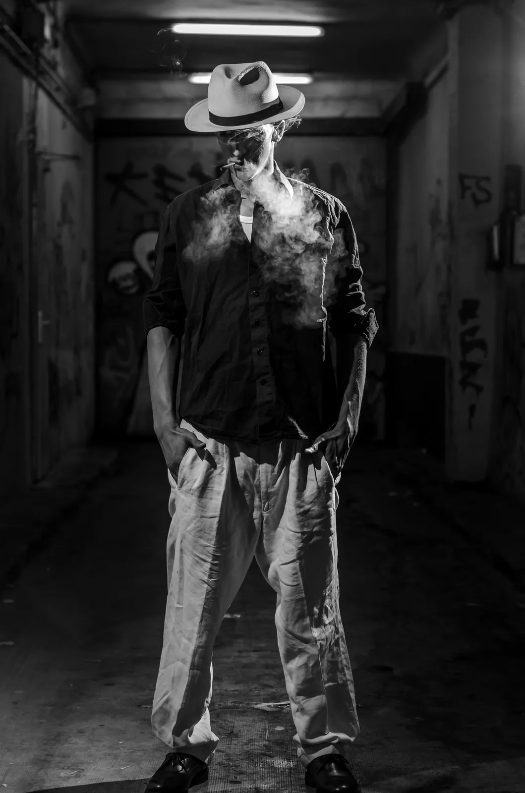 Person in a light hat standing in a dark corridor in black and white