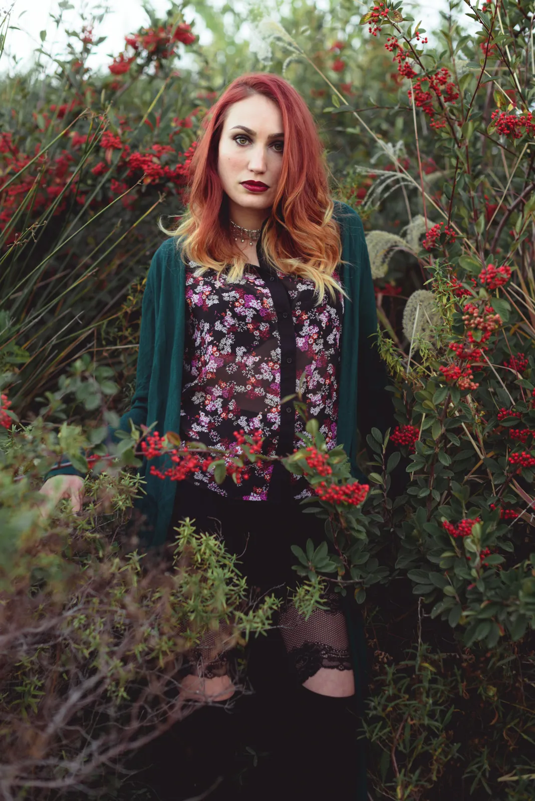 Red-haired woman standing among flowers.