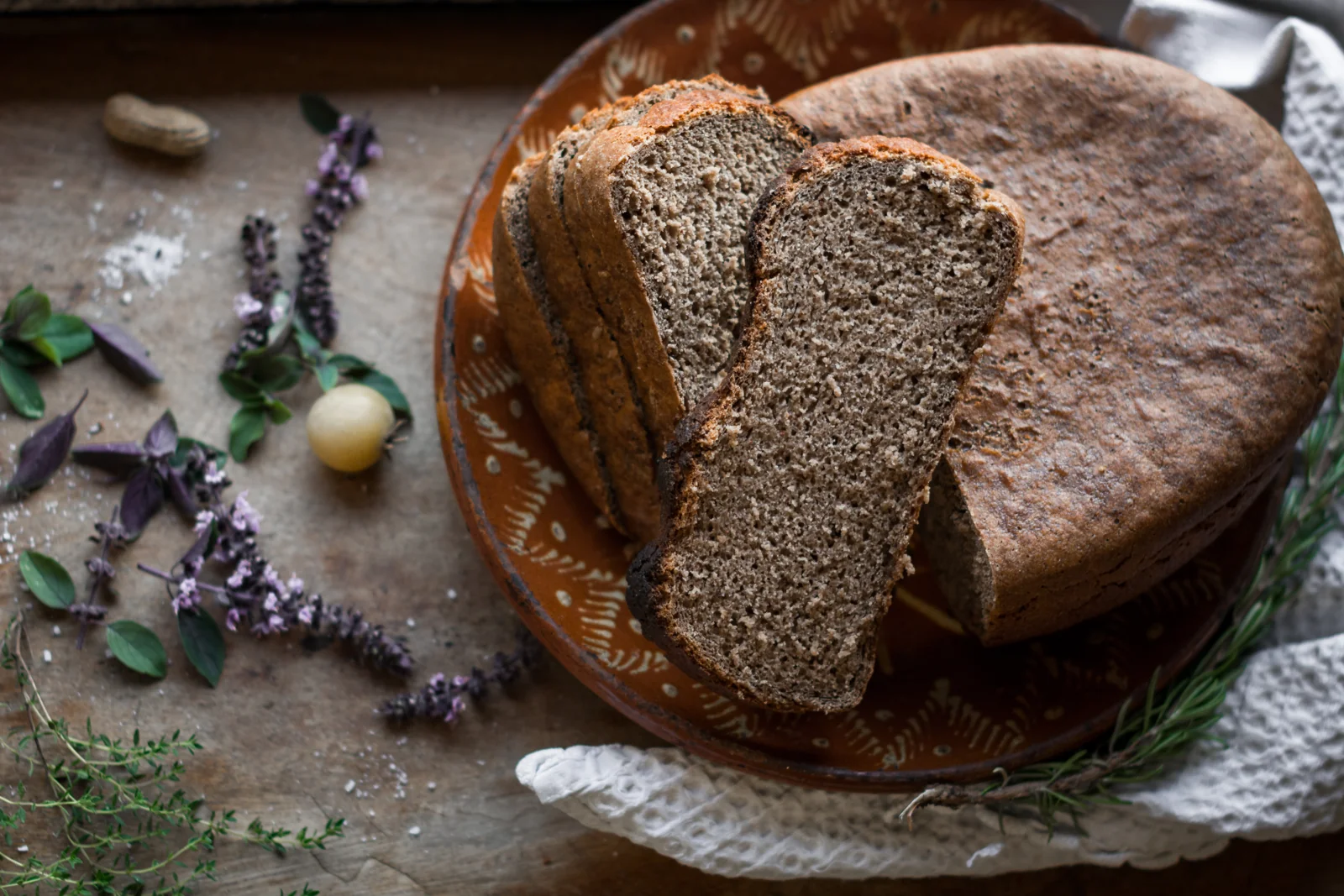 Round loaf with sliced bread and herbs.