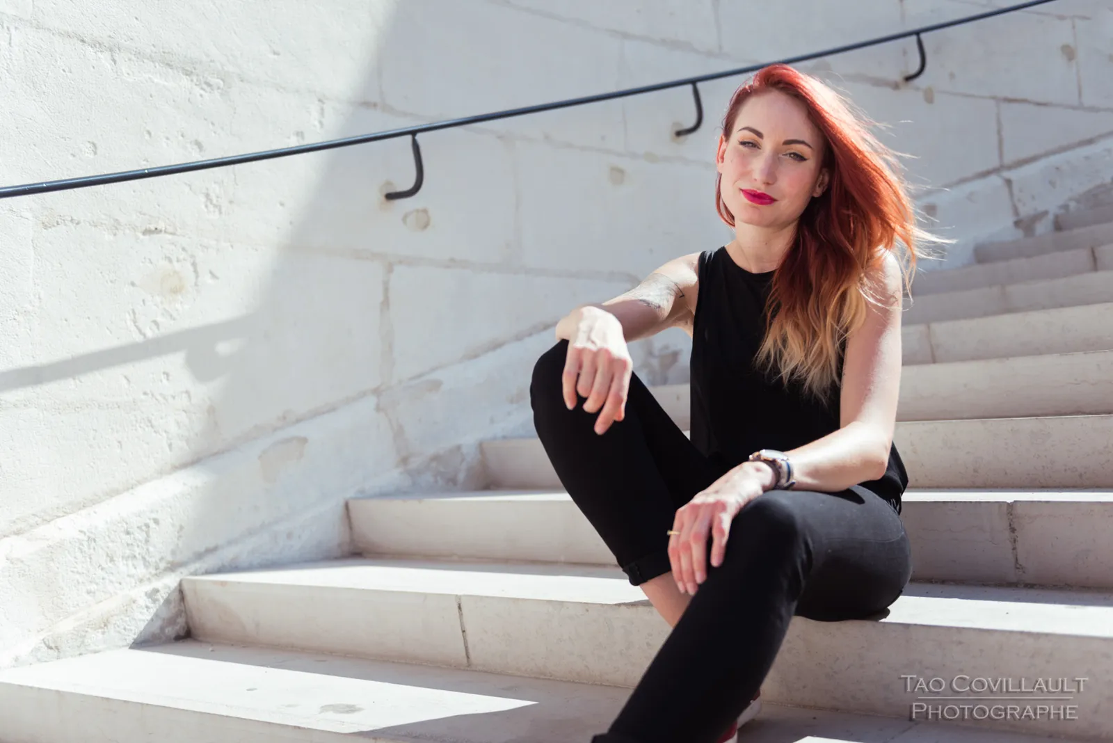 Woman in black clothing posing on pale stone steps.