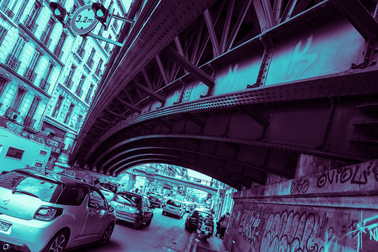 Street beneath an elevated bridge tinted cyan and purple