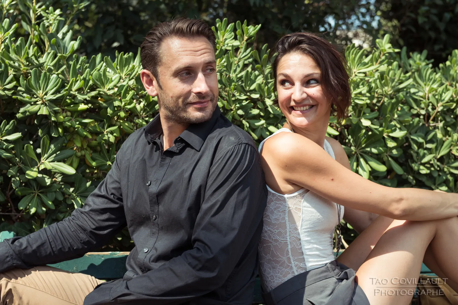 Couple sitting together beneath trees.