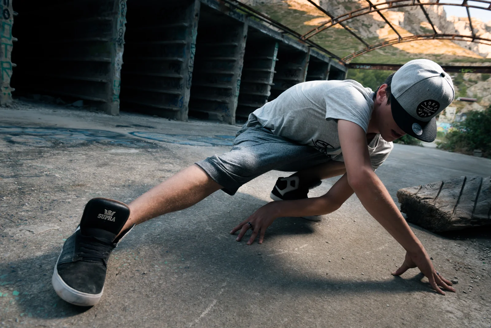 Street dancer stretching low across a concrete floor.