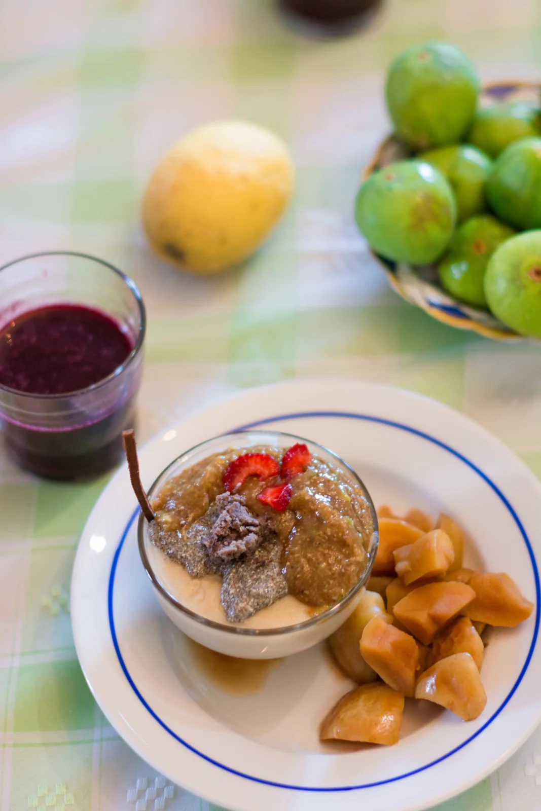 Plated meal beside fruit and a glass of drink.