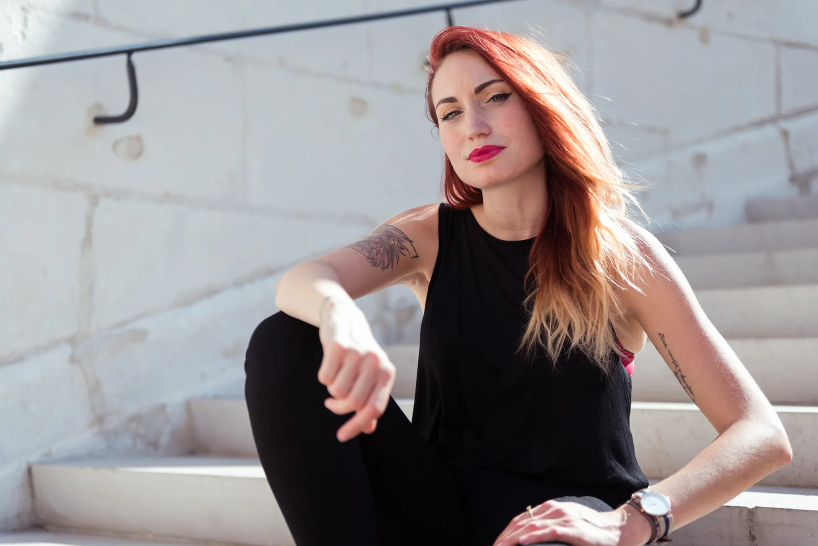 Woman in black clothing posing on pale stone steps.