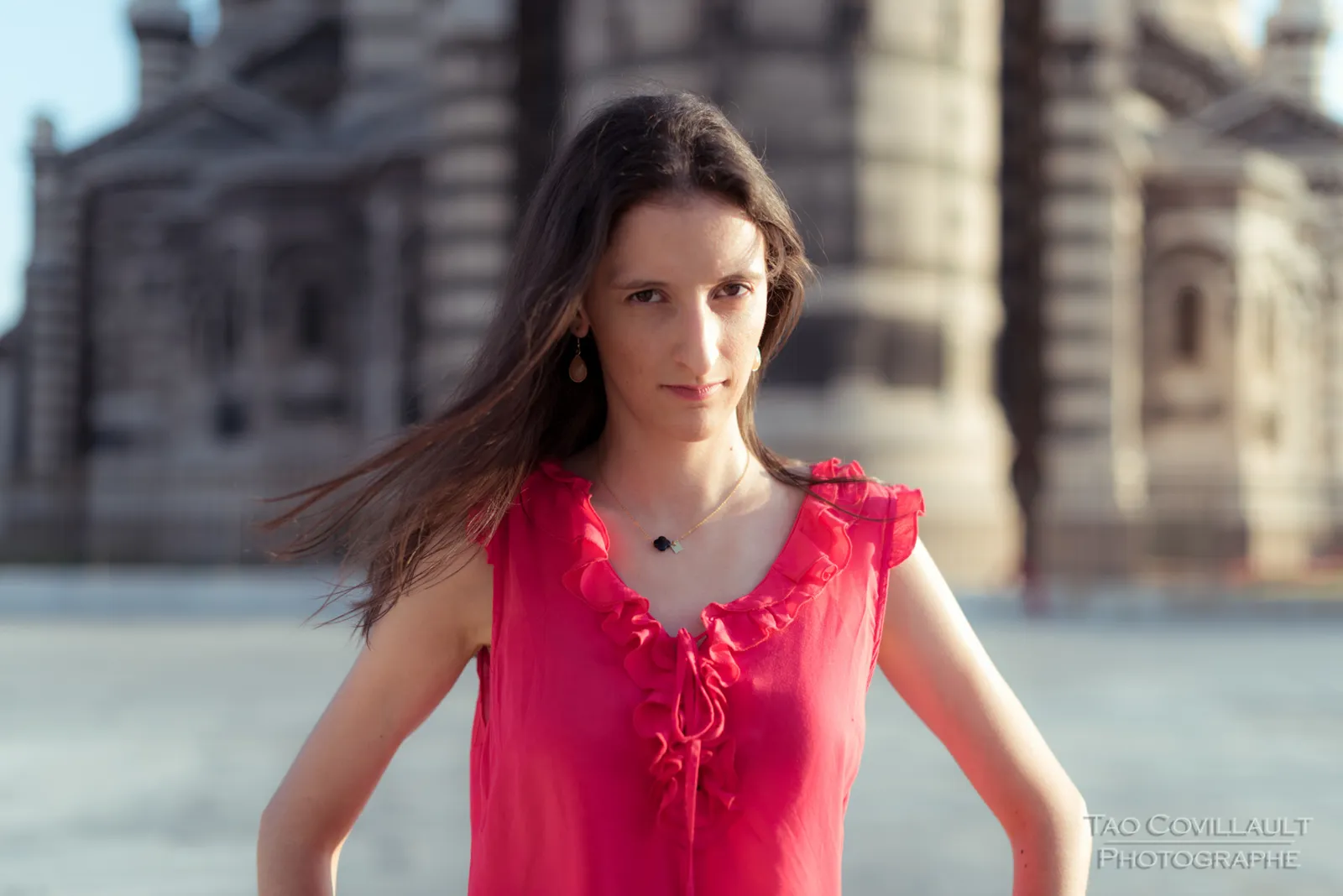 Woman in a bright pink top posing outside an ornate domed stone building.