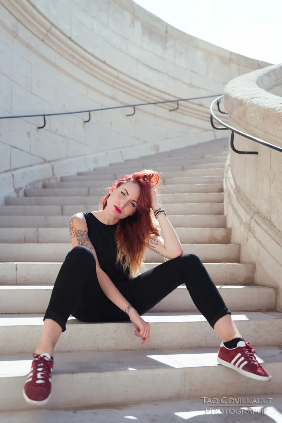 Woman in black clothing posing on pale stone steps.