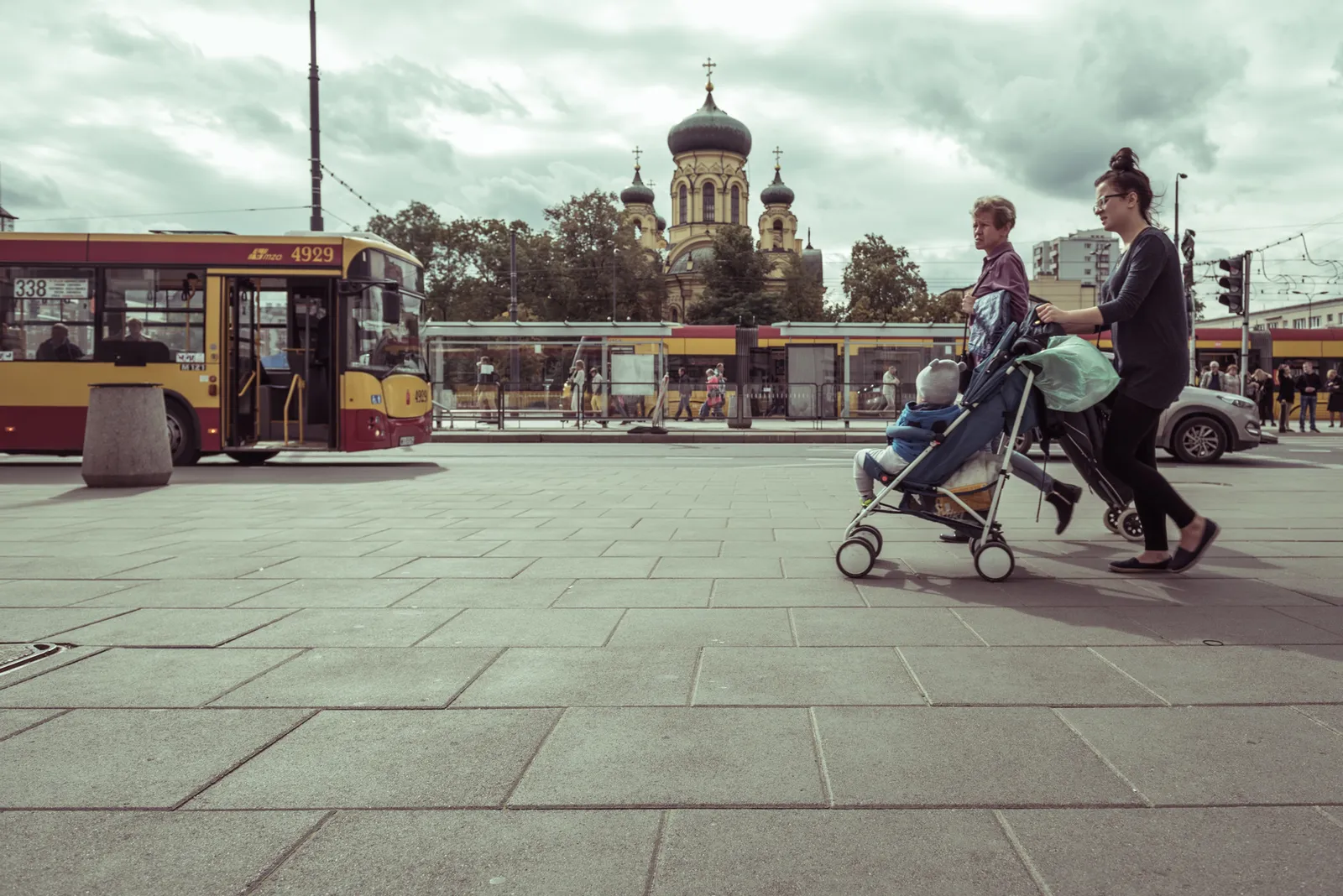 People pushing a stroller across a broad city square