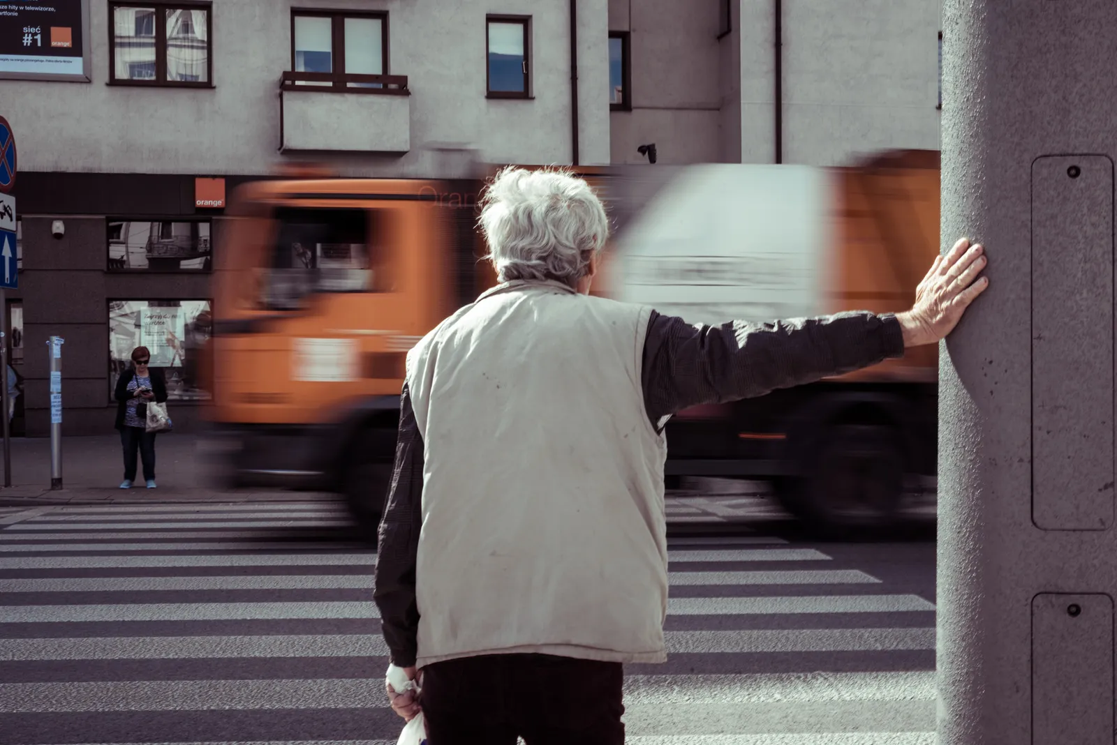 Person beside a pillar watching traffic pass