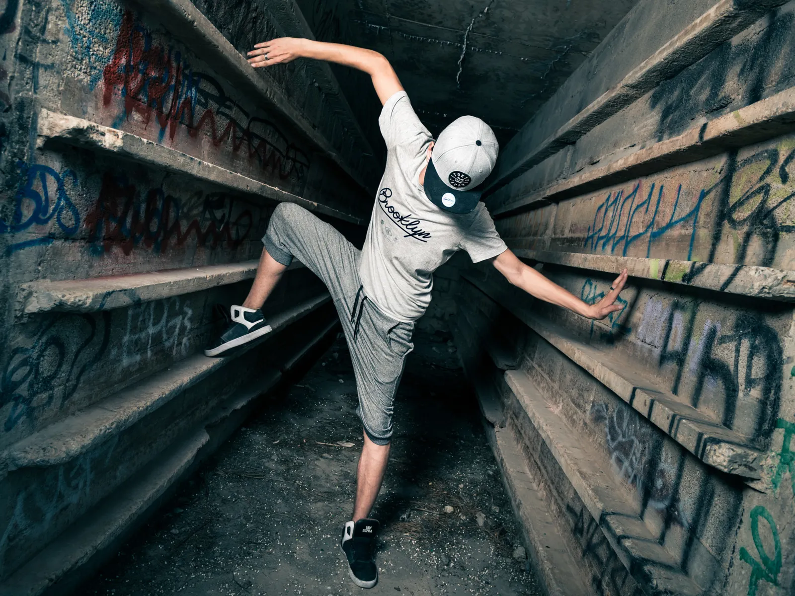 Dancer balancing between graffiti-covered walls.