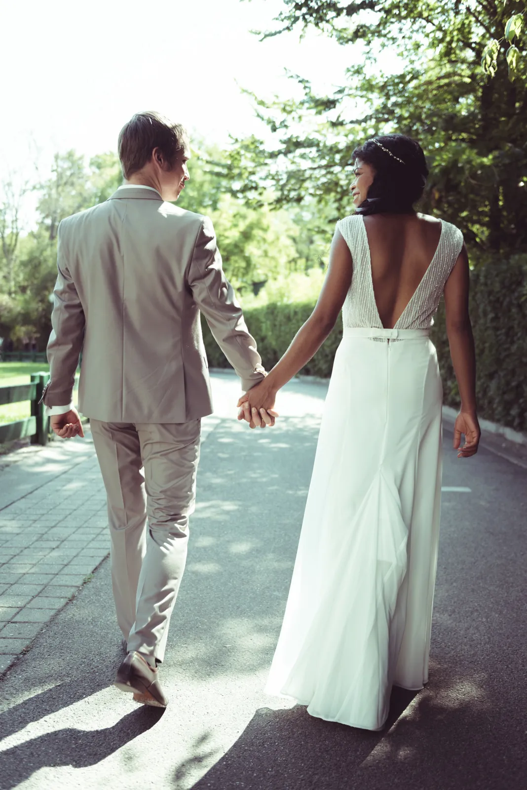 Couple walking hand in hand along a sunny path.