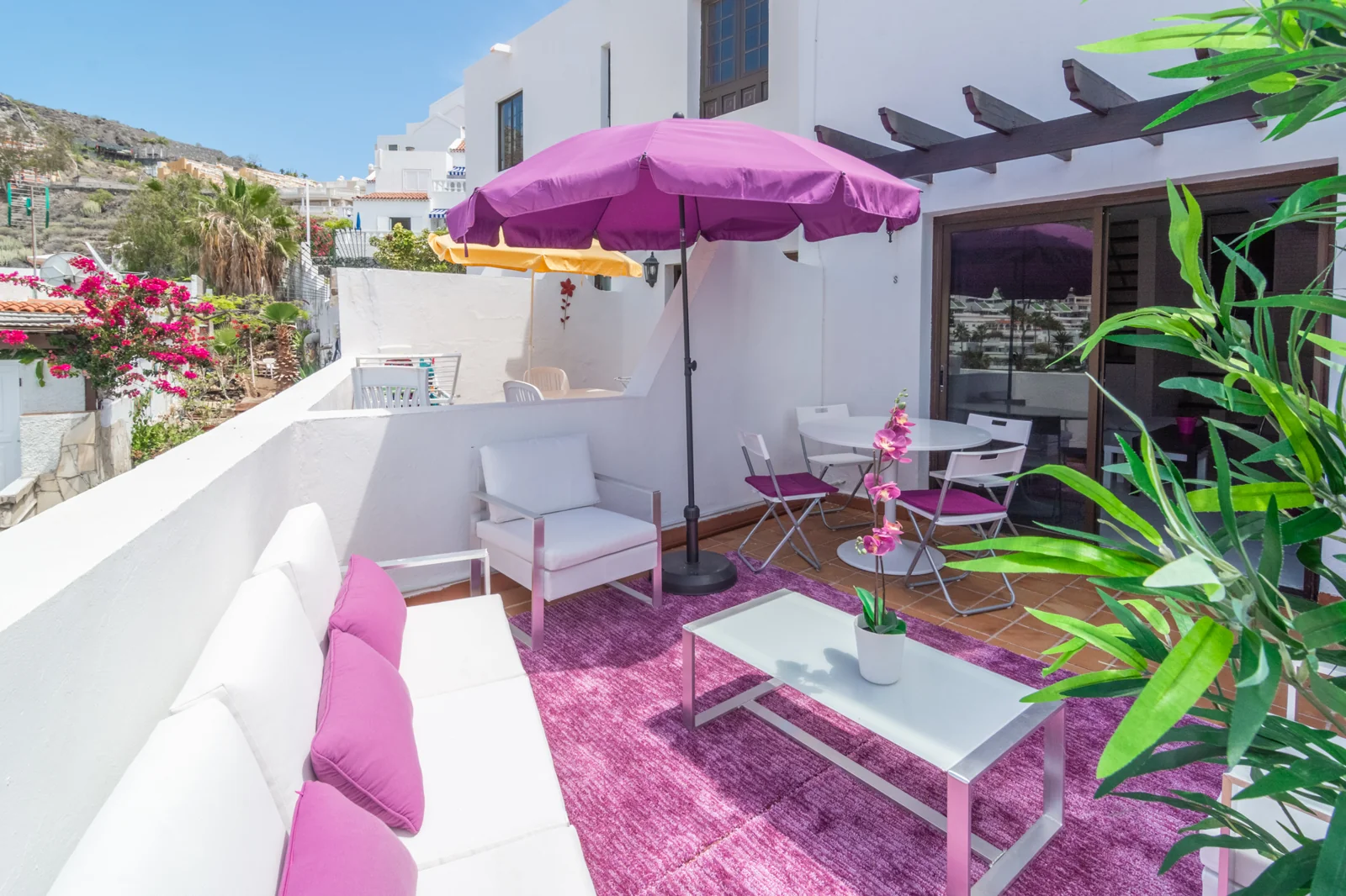 Terrace seating beneath a magenta parasol.