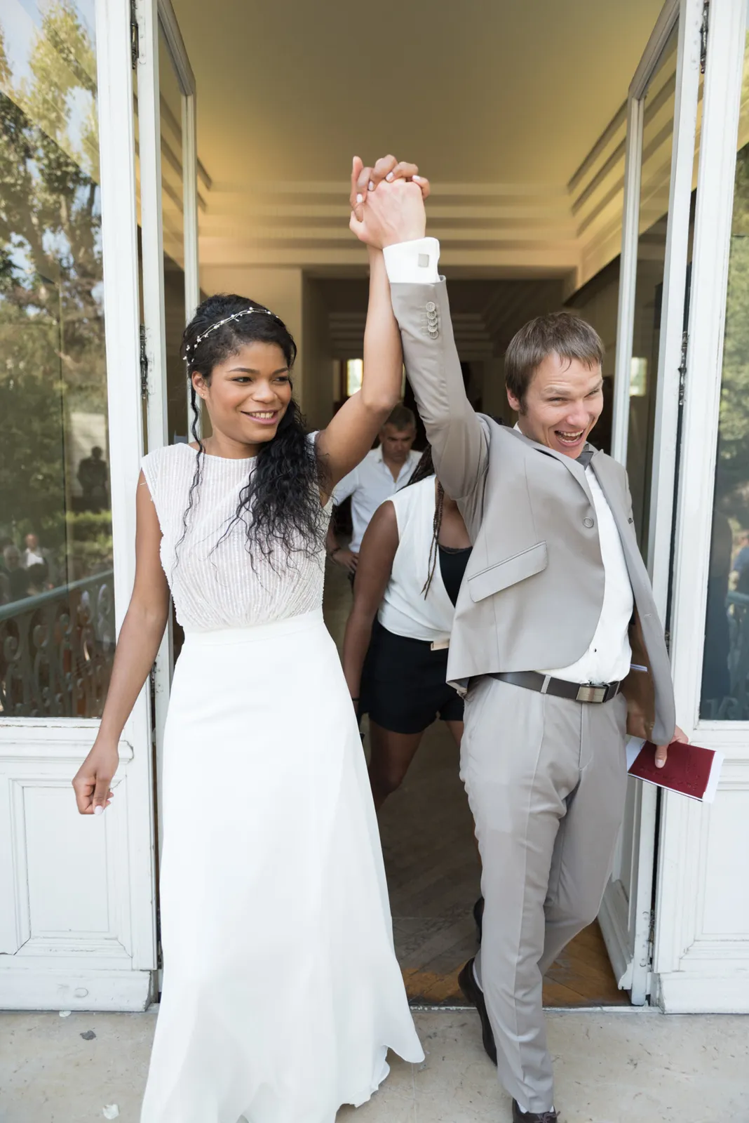 Newlyweds raising their joined hands outside the ceremony.
