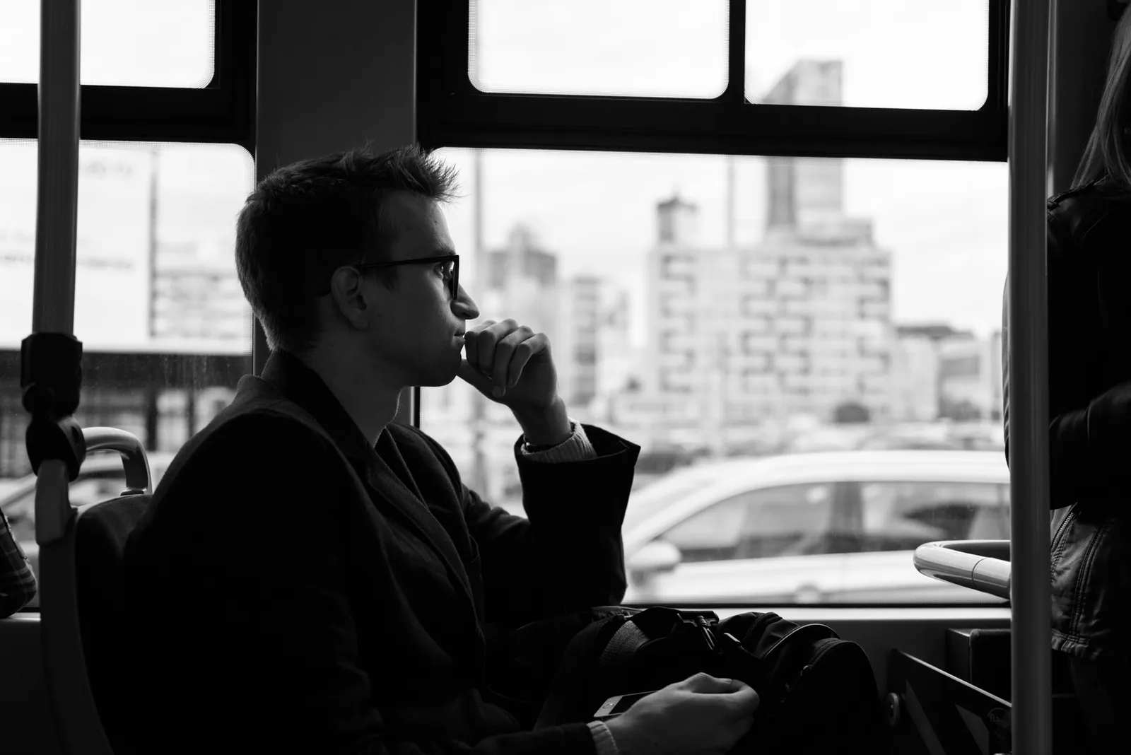 Passenger looking through a bus window in black and white