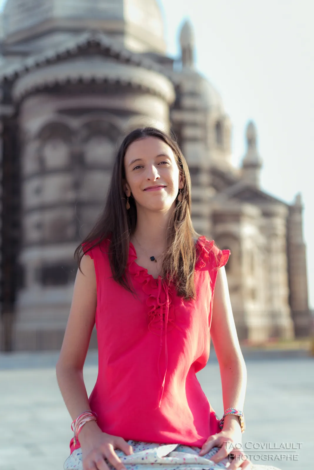 Woman in a bright pink top posing outside an ornate domed stone building.