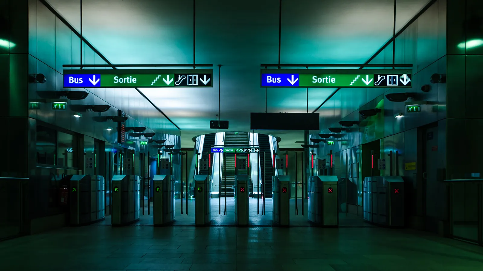 Green-lit transit station reflected symmetrically in glass