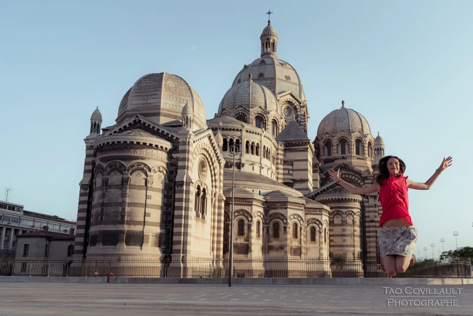 Woman in a bright pink top posing outside an ornate domed stone building.