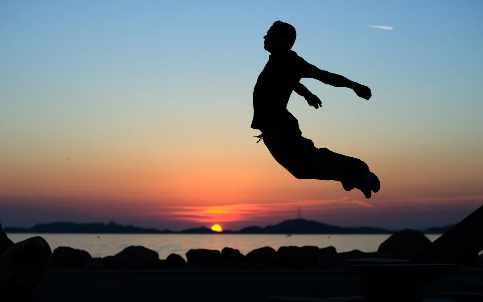 Jumping silhouette above the sea at sunset