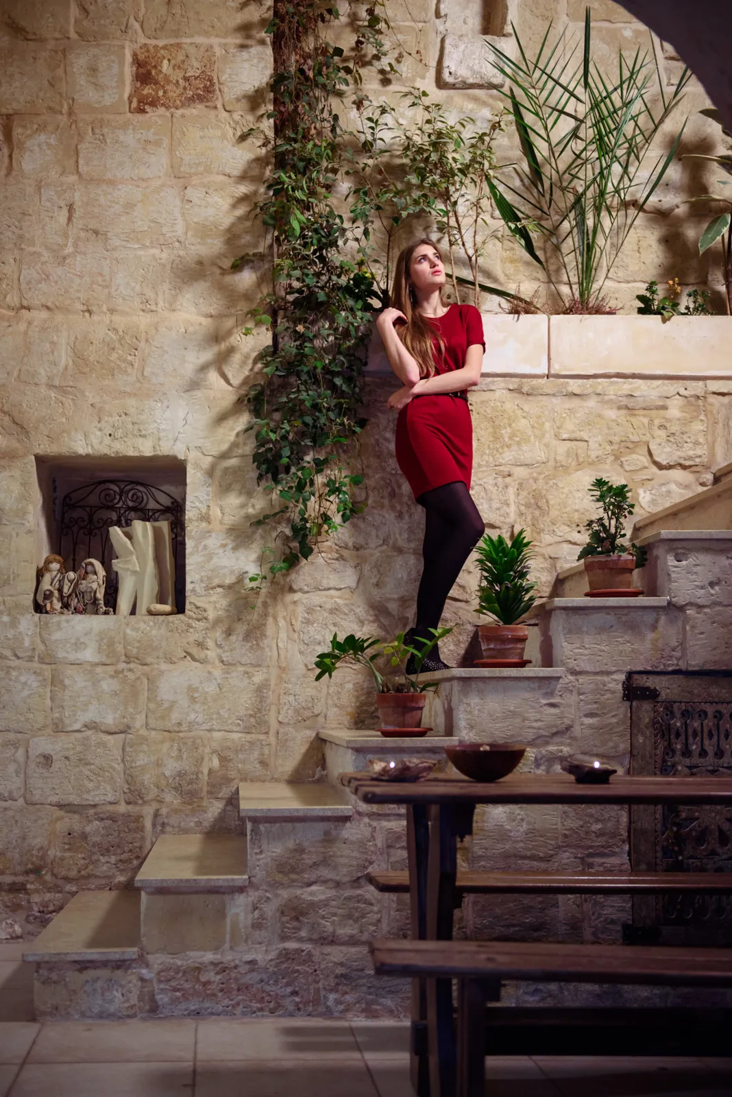 Woman in a red top standing on outdoor stone steps.