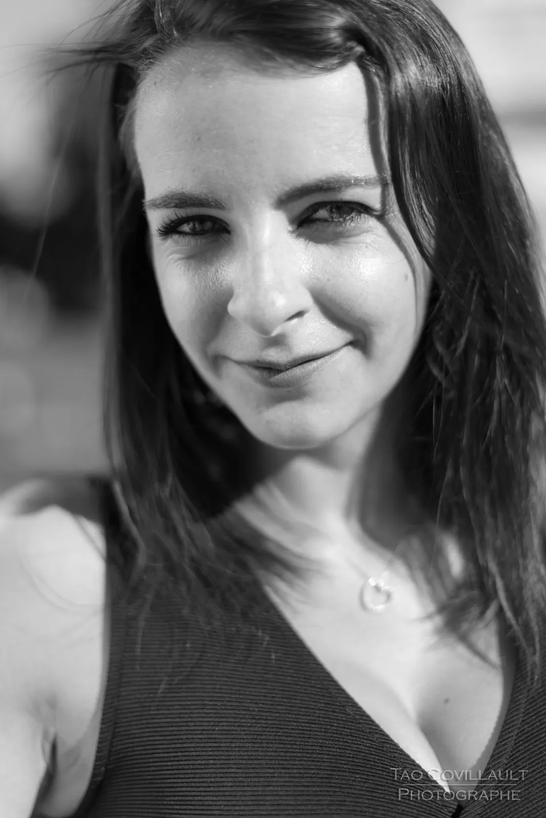 Black-and-white photograph: woman in a black dress posing among trees.