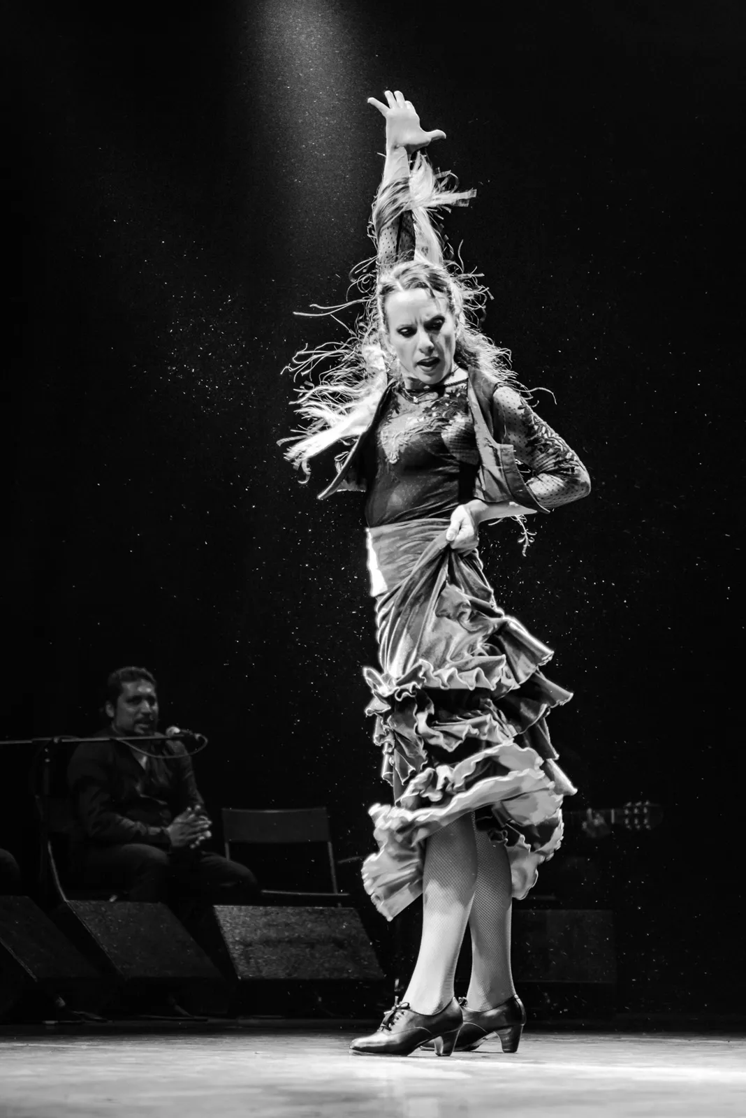 Black-and-white portrait of a flamenco dancer on stage.