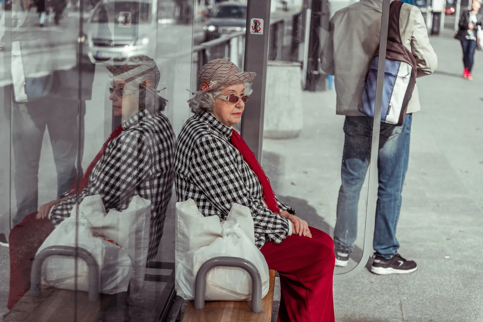 Seated passenger in red trousers reflected in glass