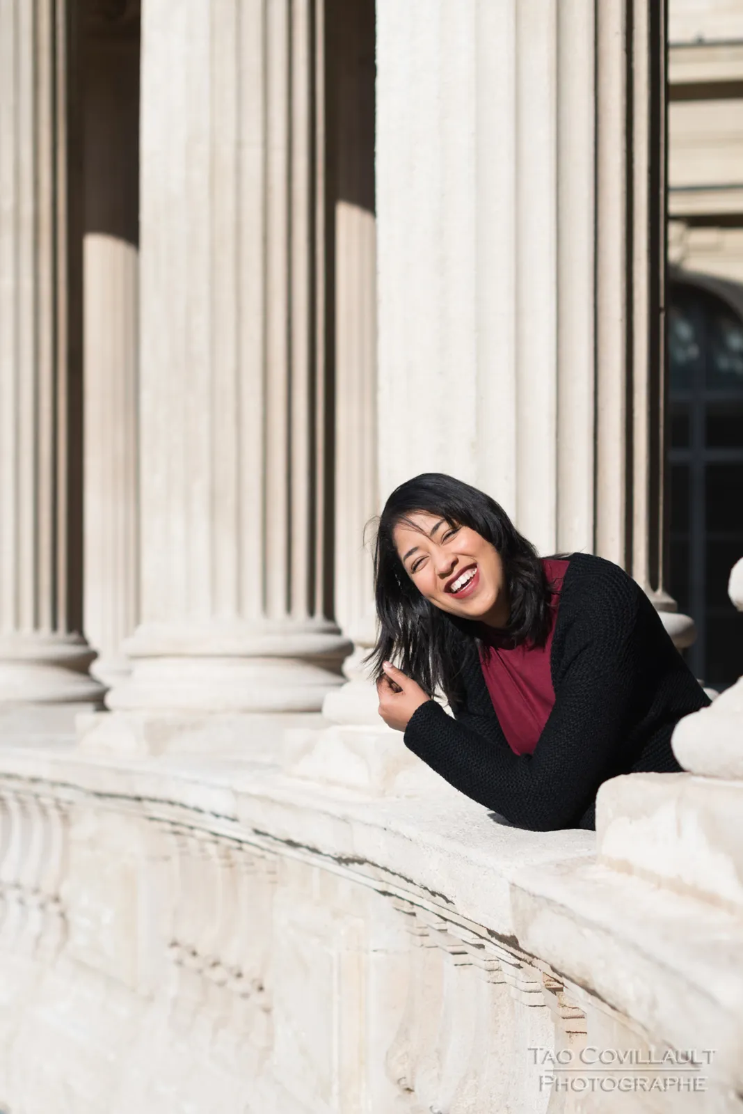 Woman leaning over a carved stone balustrade.