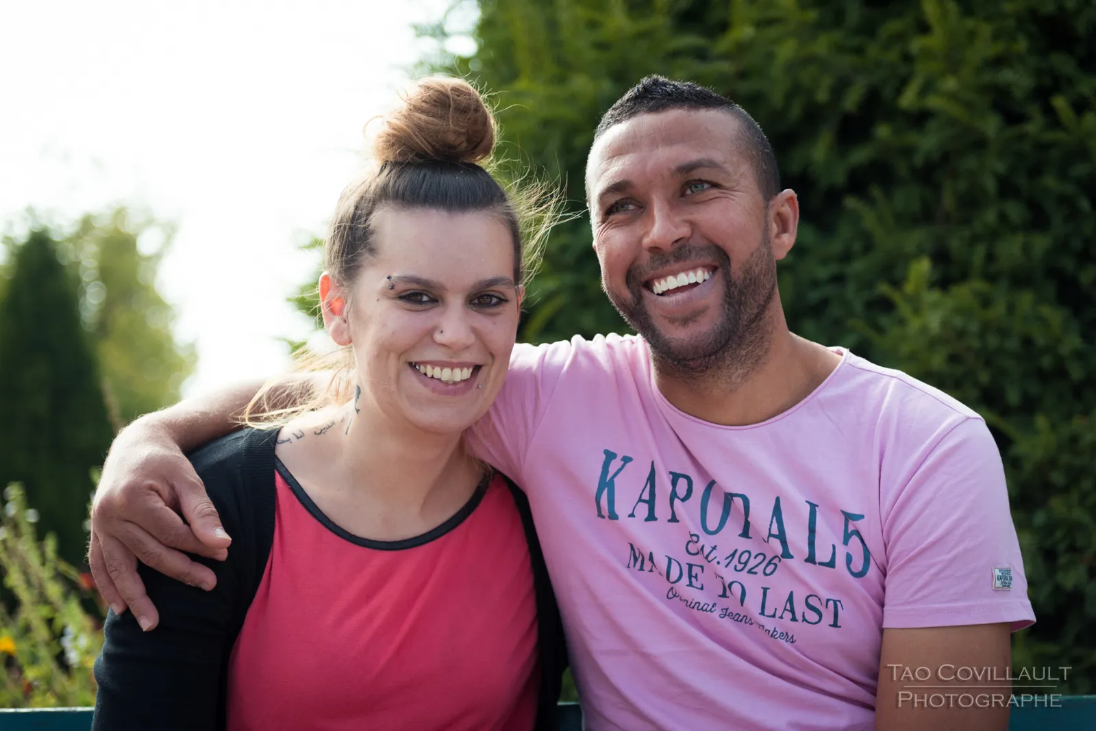 Smiling couple posing together in a leafy park.