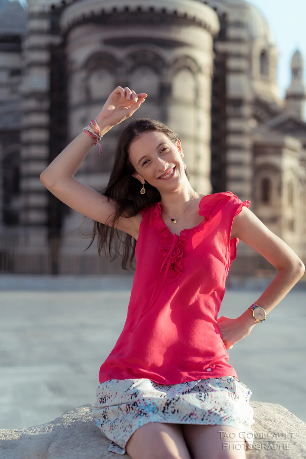 Woman in a bright pink top posing outside an ornate domed stone building.