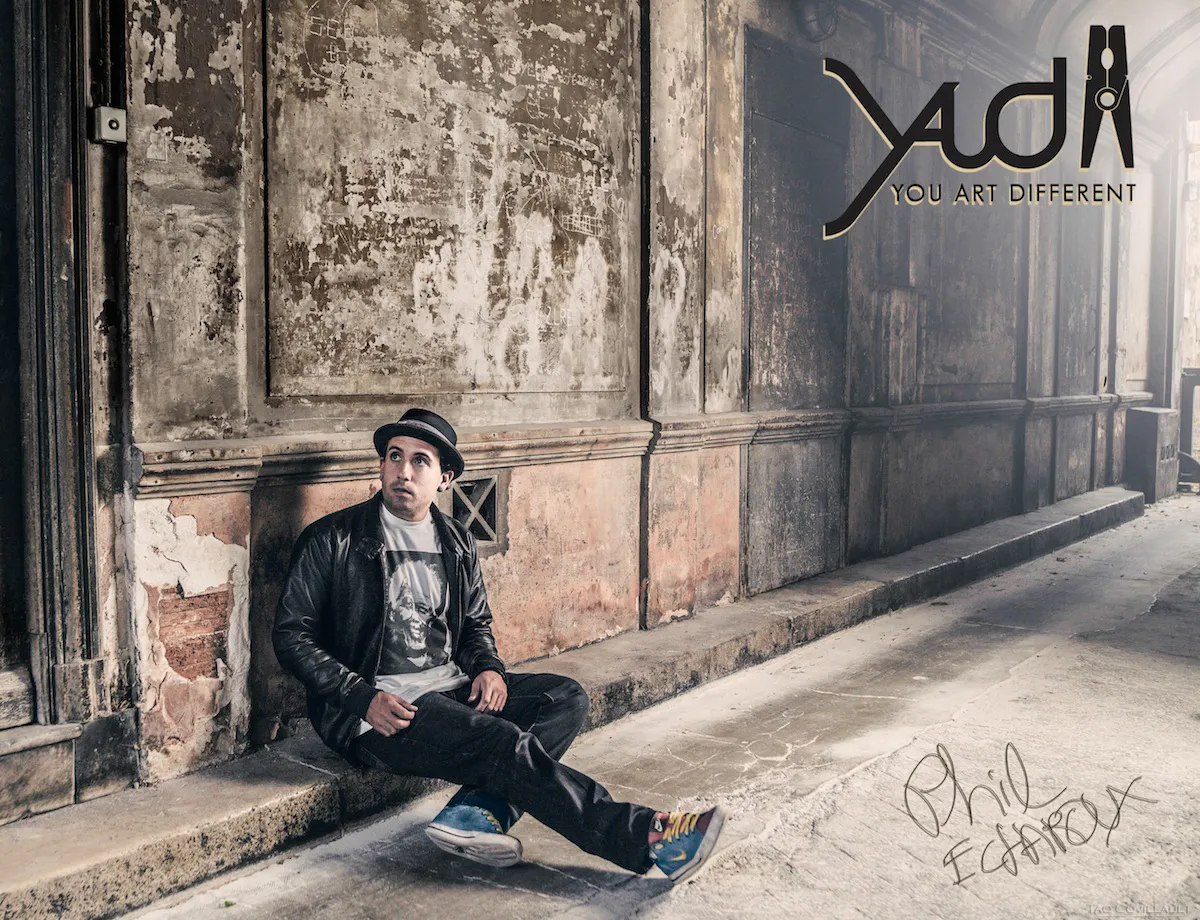 Person seated outside a weathered building with graphic lettering