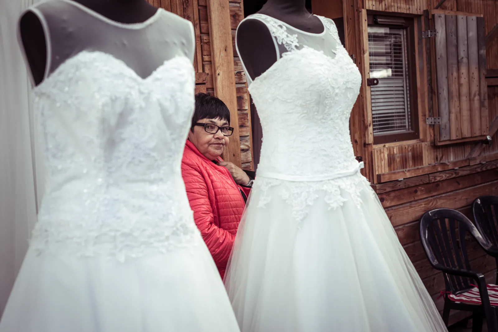 Person framed between two white wedding dresses in a shop