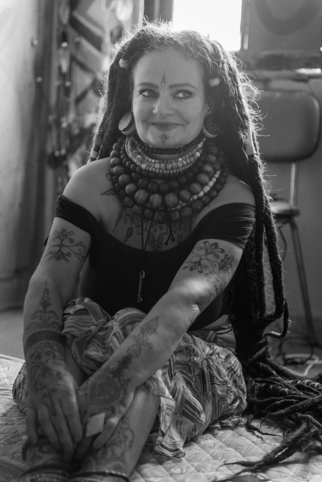 Black-and-white photograph: woman in patterned clothing seated outdoors.