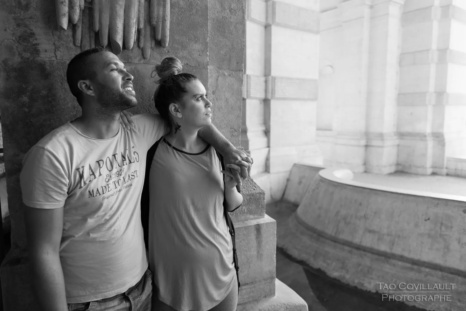 Black-and-white photograph: couple standing side by side in a stone arcade.