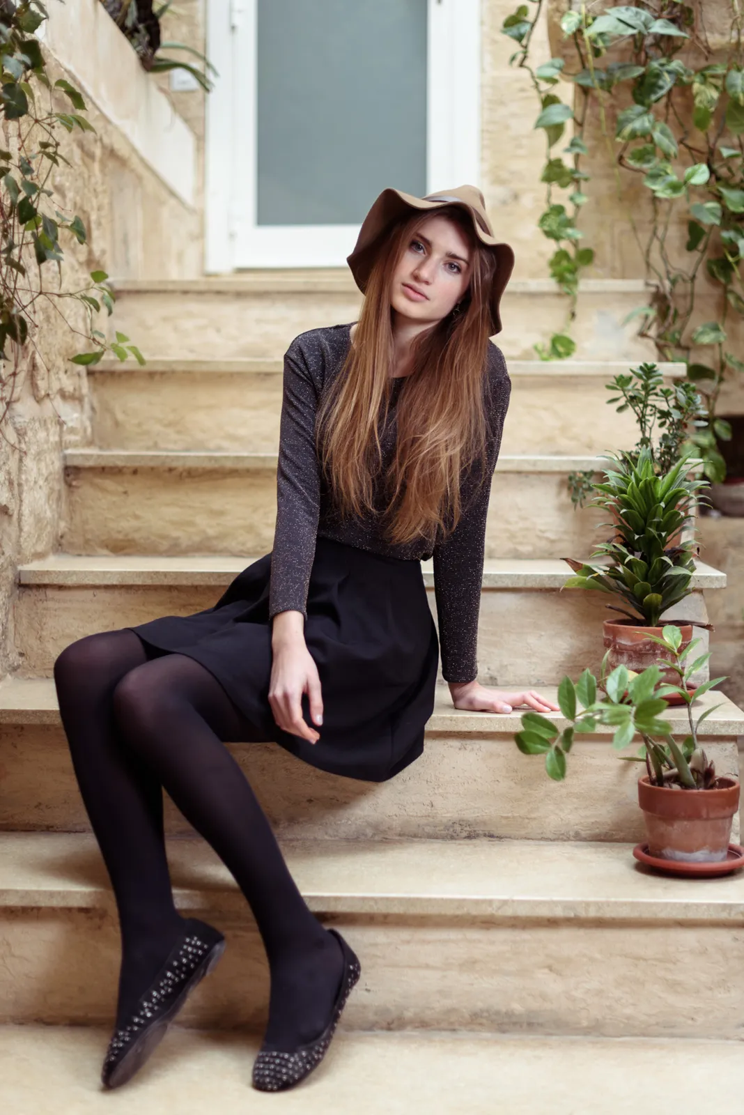 Woman dressed in black seated on stone steps.
