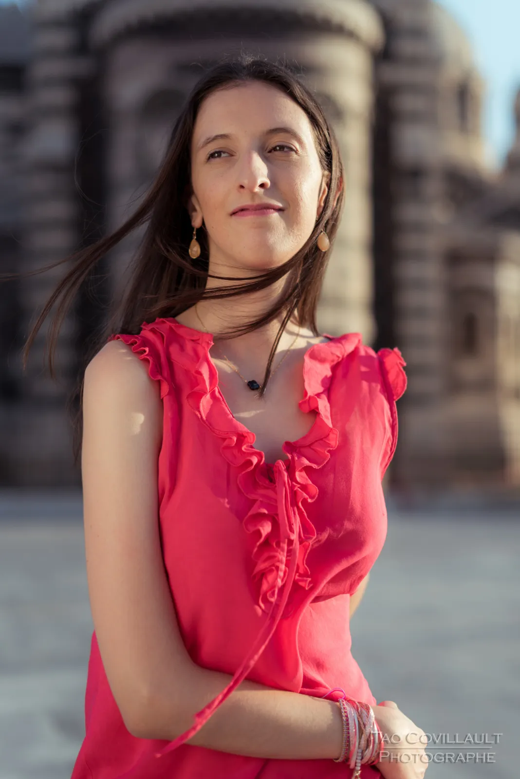 Woman in a bright pink top posing outside an ornate domed stone building.