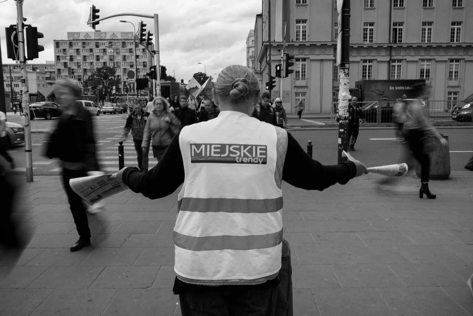 Person in a reflective vest directing pedestrians in black and white