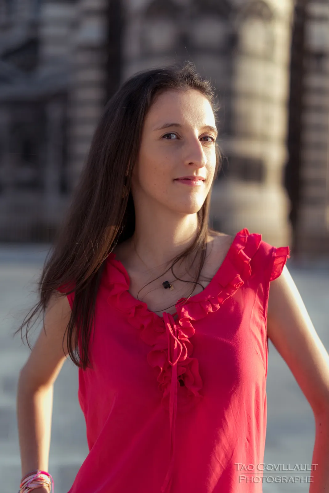 Woman in a bright pink top posing outside an ornate domed stone building.
