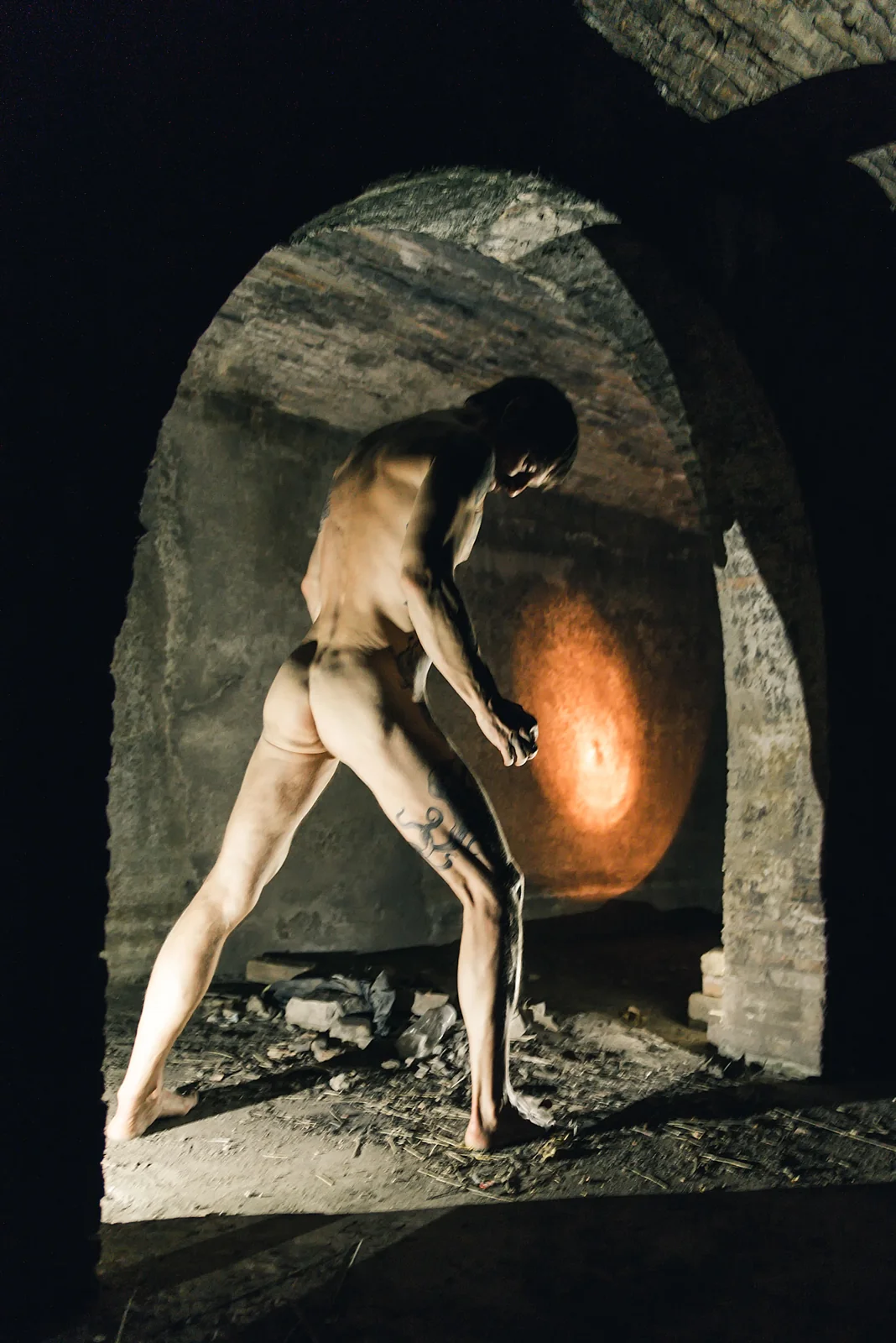 Figure and warm light beneath a stone arch