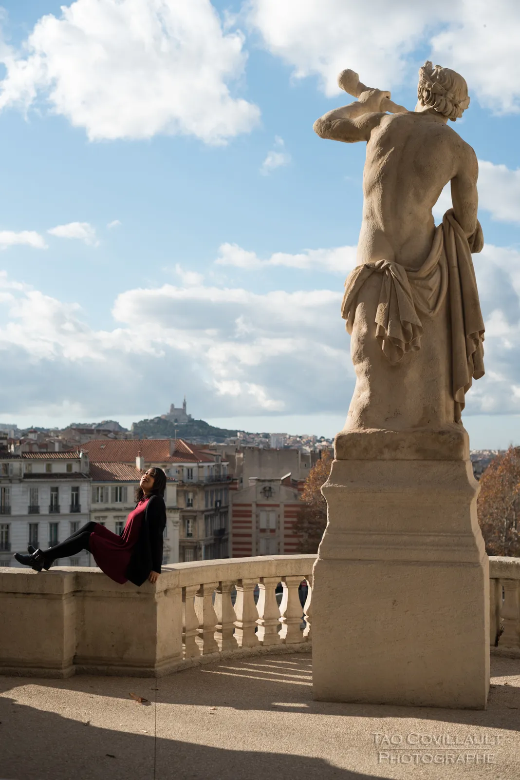 Woman seated on a stone parapet overlooking the city.