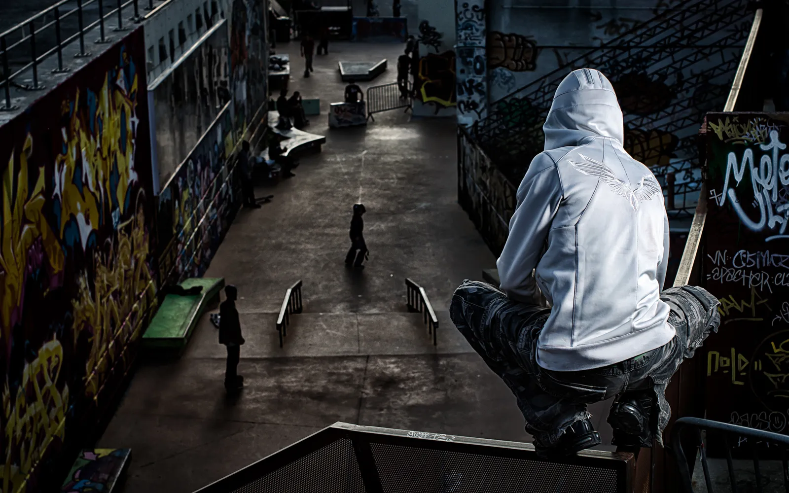 Hooded figure perched above a graffiti-covered interior