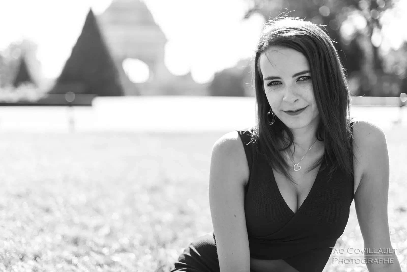 Black-and-white photograph: woman in a black dress relaxing on grass.