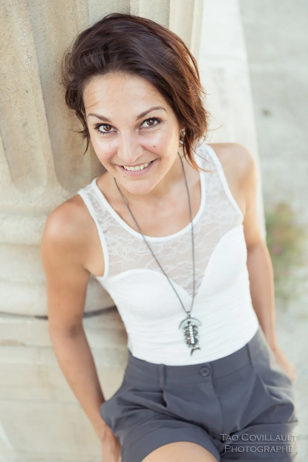 Woman in a white sleeveless top smiling toward the camera.