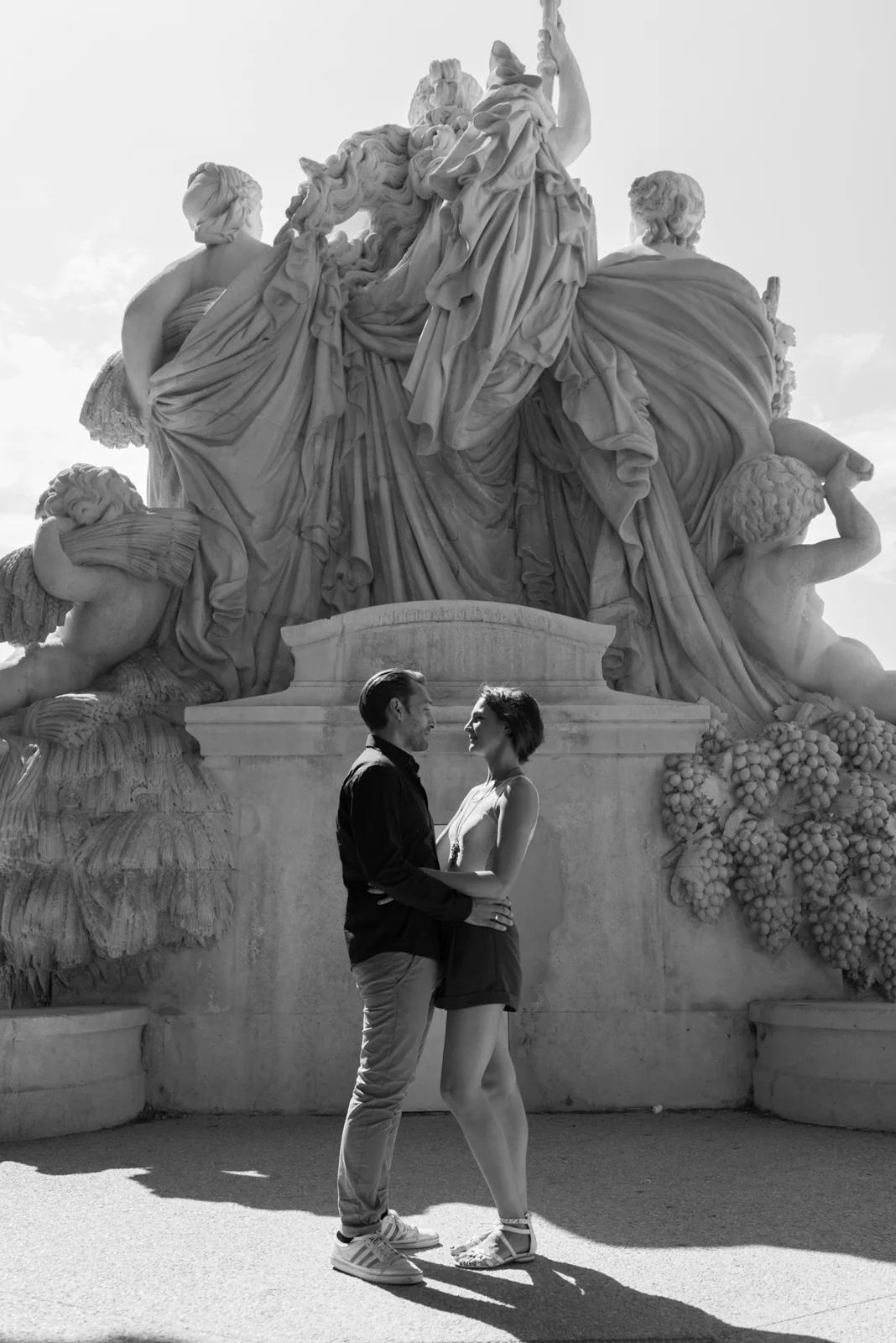 Black-and-white photograph: couple seen from behind beside ornate stone architecture.