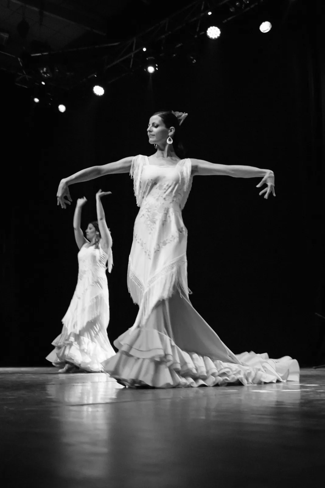 Black-and-white stage photograph of a dancer in a flowing white dress.