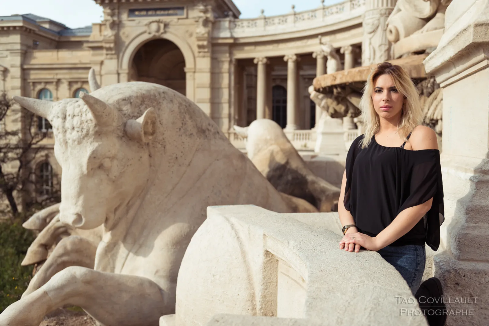 Woman in a black top standing beside a carved stone lion.