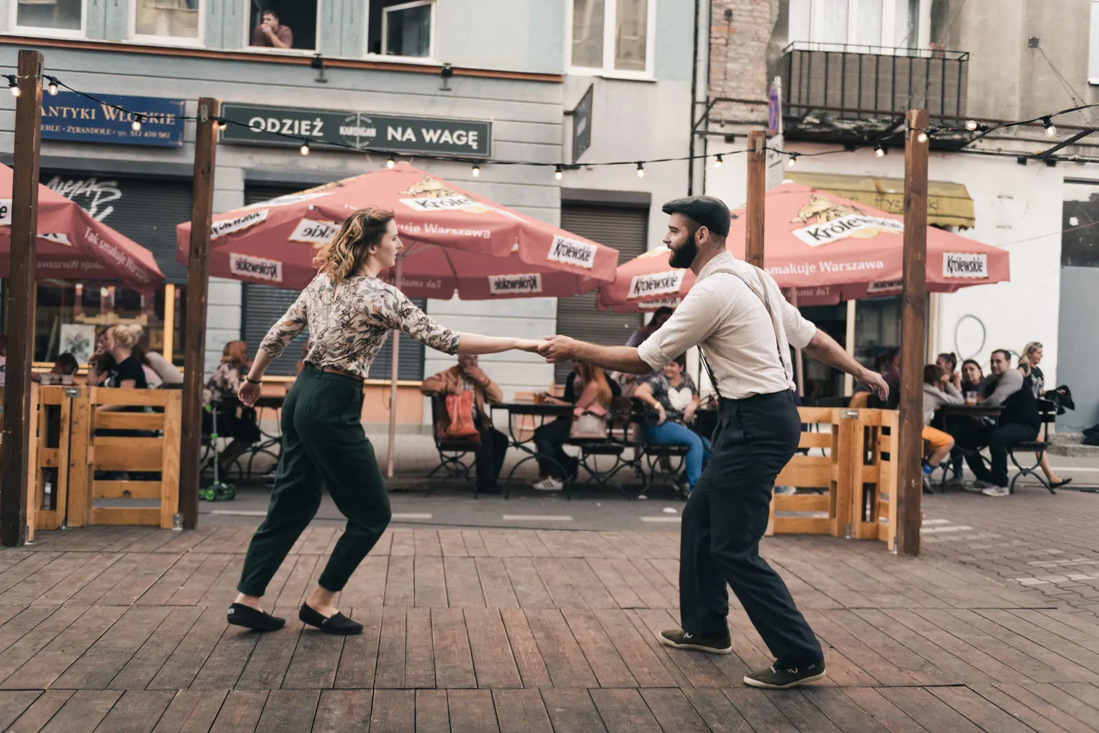 Two people dancing outside a street cafe