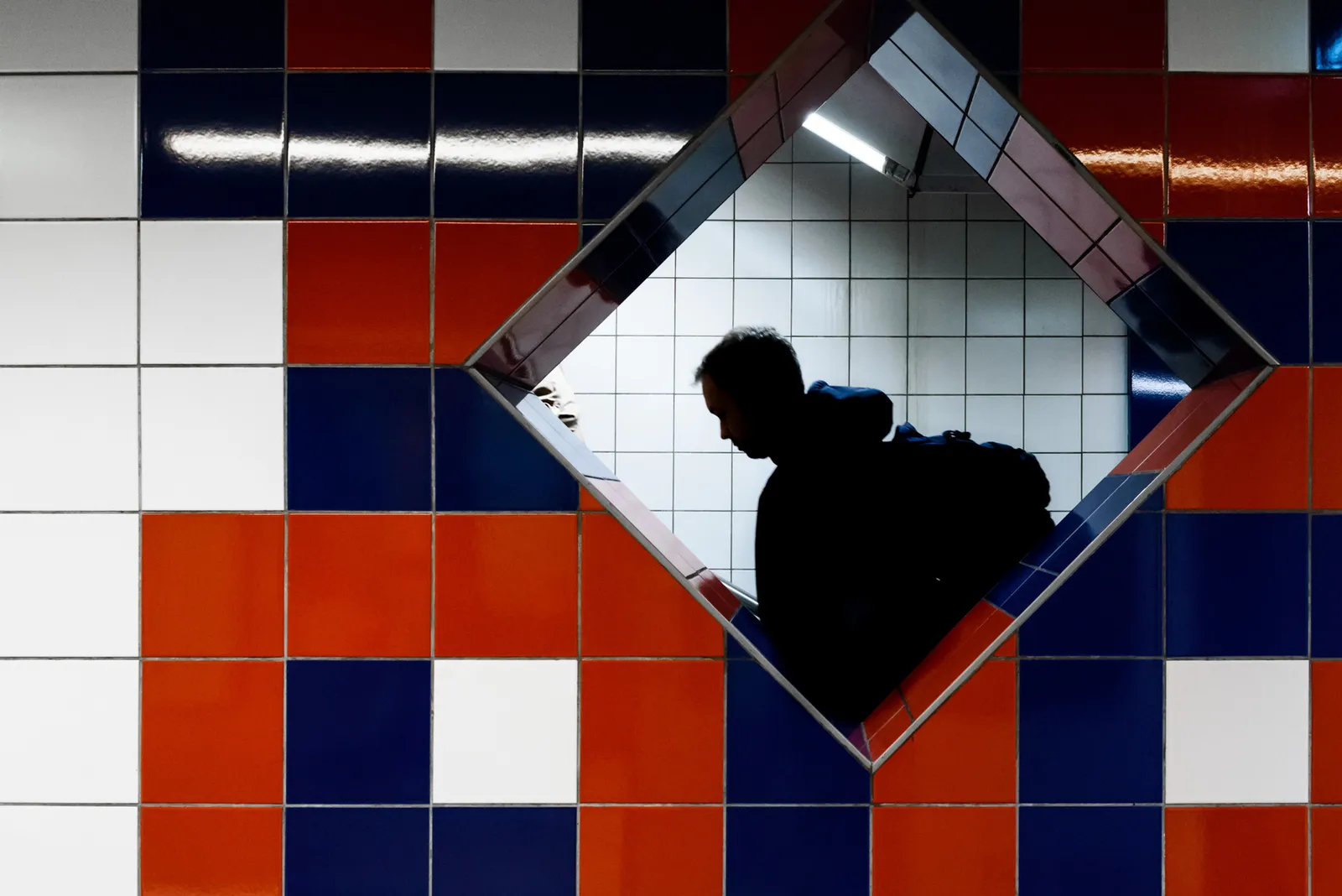 Silhouette reflected in a diamond-shaped mirror among colorful tiles